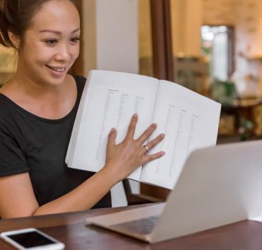 Portrait shot of mature woman teaching English to her students through video call, in front of her laptop at home , during Covid 19 lockdown